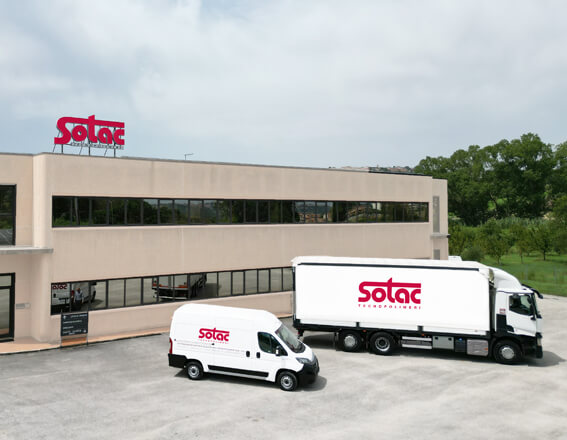Sotac-Firmengebäude mit Lieferwagen und Lkw im Vordergrund, markante rote Logos sichtbar.