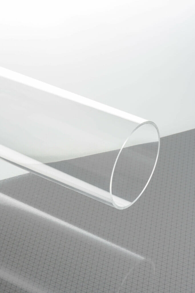 Transparente Acrylröhre auf kariertem Hintergrund, ideal für kreative Designprojekte und industrielle Anwendungen.