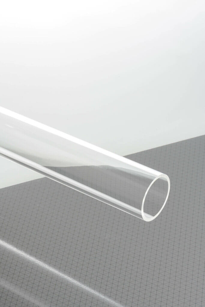 Klares Kunststoffrohr auf Rasterhintergrund, ideal für industrielle Anwendungen und kreative Projekte.