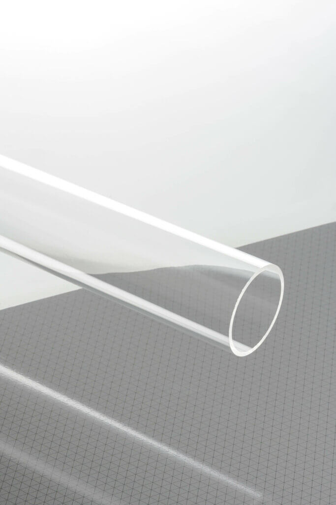 Klares Acrylrohr auf grauem Gitterhintergrund, ideal für DIY-Projekte und industrielle Anwendungen.