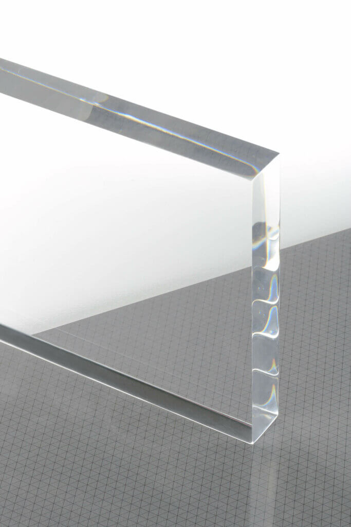 Klares Acrylglas auf kariertem Hintergrund, Lichtspiel zeigt transparente und saubere Kanten für präzise Anwendungen.