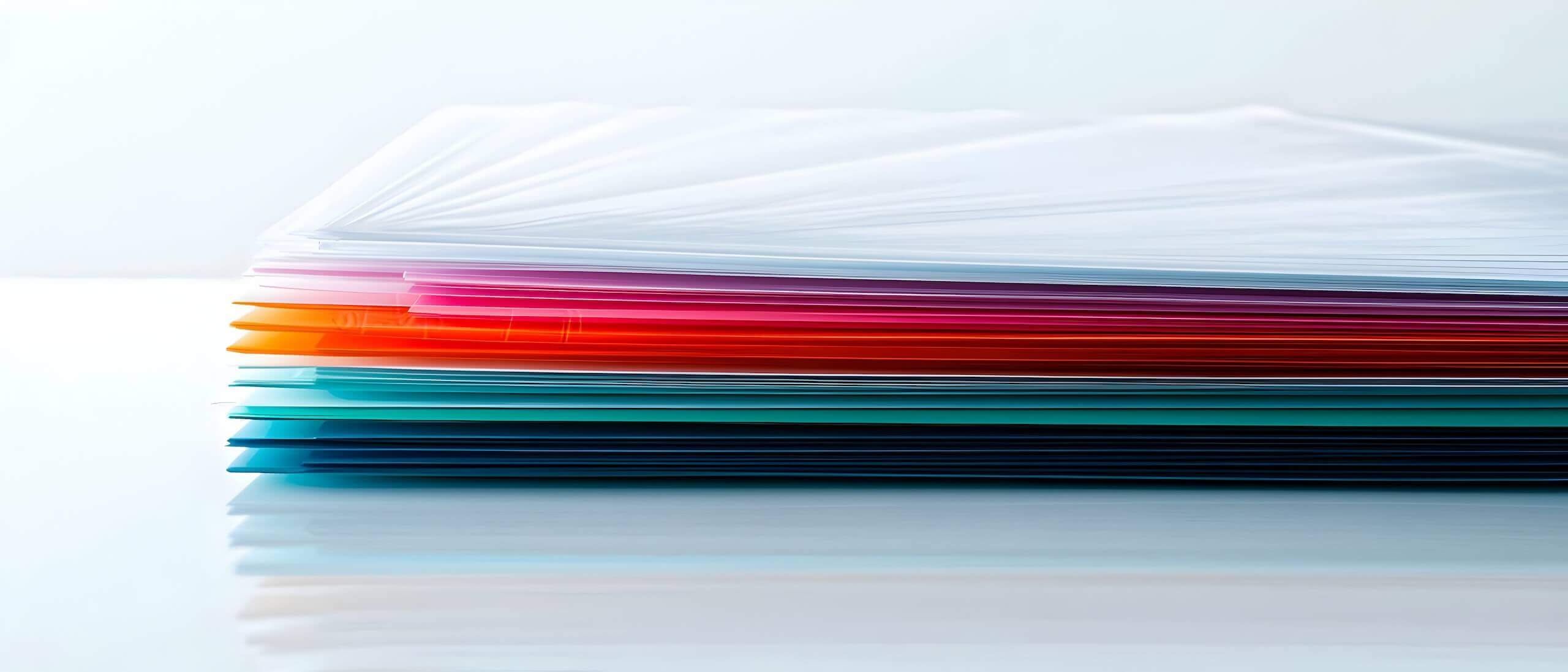 Bunte Papierstapel auf einem Tisch, gestapelt in verschiedenen Farben für kreative Projekte und Büroorganisation.
